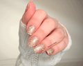 Hand with glittery gold nail wraps on a neutral background