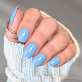 Hand with light blue nail wraps wearing a white textured sleeve against a neutral background