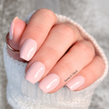 Close-up of a hand with light peach nail polish stickers wearing a white textured sleeve.
