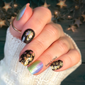 Hand with decorated lucky clover nails wraps against a wooden background