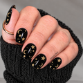 Midnight Prophecy black nail wraps with metallic gold crescent moons, stars and celestial details on a hand.