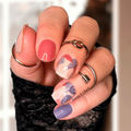 Close-up of a hand with palm tree nail stickers wearing rings against a blurred background