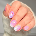 Hand with pastel-colored nail wraps featuring butterfly designs, held against a neutral background.