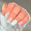 Pastel daisy nail wraps with yellow, mint, pink, and floral accent nails on hand