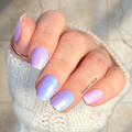 Hand with pastel purple and blue nail stickers on a light background