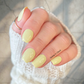 Hand with light yellow nail stickers on a neutral background