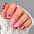 Pink and red glitter Christmas nail wraps with gingerbread, candy cane hearts, a Santa hat and white gift bows on a hand.