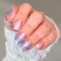 Hand with pink and purple gradient nail wraps and a white textured sleeve.