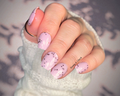 Close-up of a hand with pink nail wraps with pink chunky glitter, wearing a white textured sleeve.