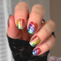 Hand with multicolored glittery nail polish strips against a neutral background