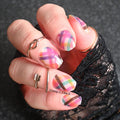 Close-up of a hand with colorful nail art on a dark background