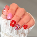 red and pink themed nail wraps set. The nails feature a mix of solid pink, glossy red, a geometric mandala pattern in pink, white, and red, and a thin gold accent line.