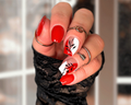 Hand with red nail and white polish wraps with a black leaf design.