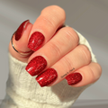 Hand with red glittery nail polish stickers on a neutral background