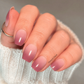 Rosewood Haze mauve ombré nail wraps with a creamy sheer white base fading into soft rosewood mauve tips, shown on a hand wearing a cozy white sweater.