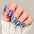 Hand wearing Siren’s Veil nail wraps with blue and teal marbled nails and shimmering blue and violet accent nails