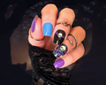 Hand with colorful skull and bat nail wraps and black lace glove on a dark background