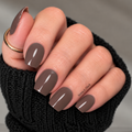 Smoked Walnut cool-toned brown nail wraps with grey undertones and a glossy finish, shown on a hand wearing a black knit sweater.