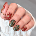 Hand wearing Snip Snap Gift Wrap Christmas nail wraps with red and forest-green glitter and gold gift, ornament, holly and bell designs.