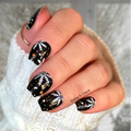 Hand with black and white snowflake  nail art stickers wearing a white sleeve