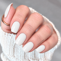 Something Borrowed soft white nail wraps with a glossy finish on short square nails, shown with a rose gold ring and cream knit sweater