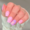 Hand wearing soft pink nail wraps with pink confetti glitter accent nail and glossy finish