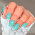 A close-up of a hand with glossy turquoise nail wraps, wearing a white knit sleeve and a gold ring, against a soft gray background.