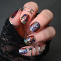 Hand with colorful glittery nail polish wearing a black textured glove on a dark background