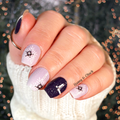 Hand with decorated navy and grey winter themed nail wraps against a blurred background